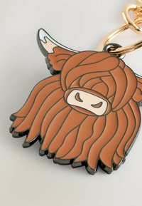 Keychain med højlandsku, der har en rund form, orange og hvide farver, tekstureret hårdesign og en guld fastgørelsesring.