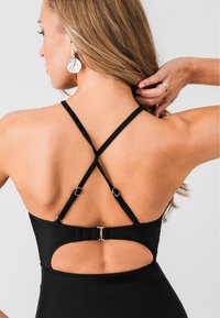 Maillot de bain noir avec un design à dos croisé, des bretelles ajustables, un détail découpé dans le dos et des accents en métal.