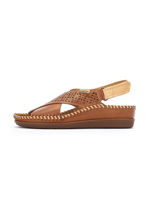 Chanclas de piel marrón con diseño perforado, abierto en la punta y con tira trasera. Presentan un detalle de costura a lo largo de la suela para añadir textura.