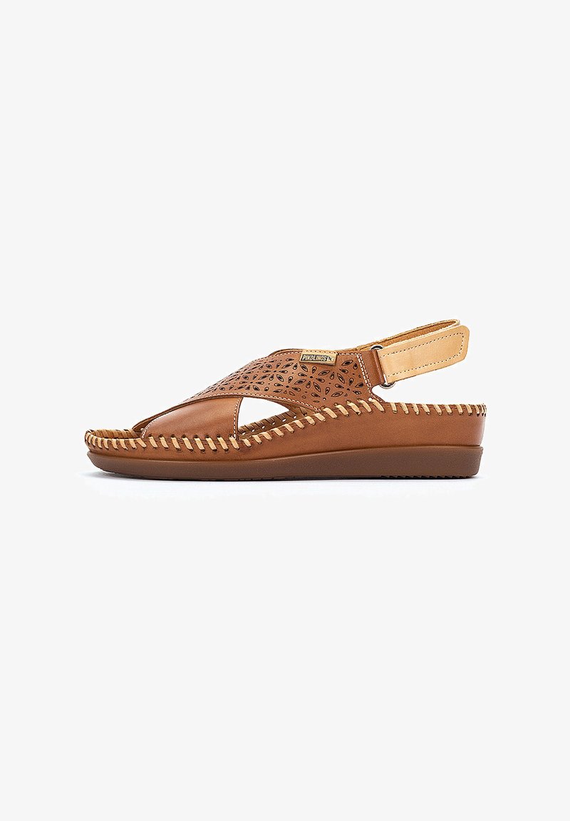 Chanclas de piel marrón con diseño perforado, abierto en la punta y con tira trasera. Presentan un detalle de costura a lo largo de la suela para añadir textura.