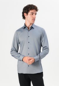 Cămașă pentru bărbați cu mânecă lungă, în albastru deschis, dintr-un material texturat. Prezintă un guler clasic, nasturi închisi la culoare și o croială ajustată.