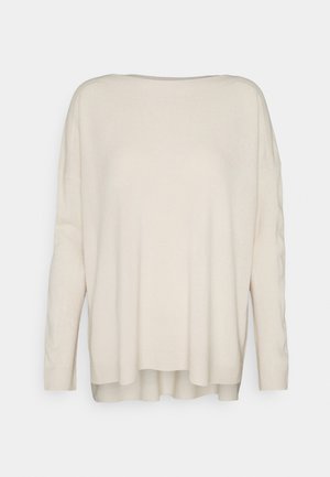 Pull en maille crème à manches longues avec une coupe ample et des poignets et un ourlet côtelés, présenté sur un fond clair uni.