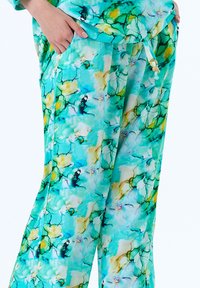 Lichte, aqua-blauwe broeken met een vloeiende stijl, met een aquarelpatroon in groen, geel en wit. Inclusief zijzakken.