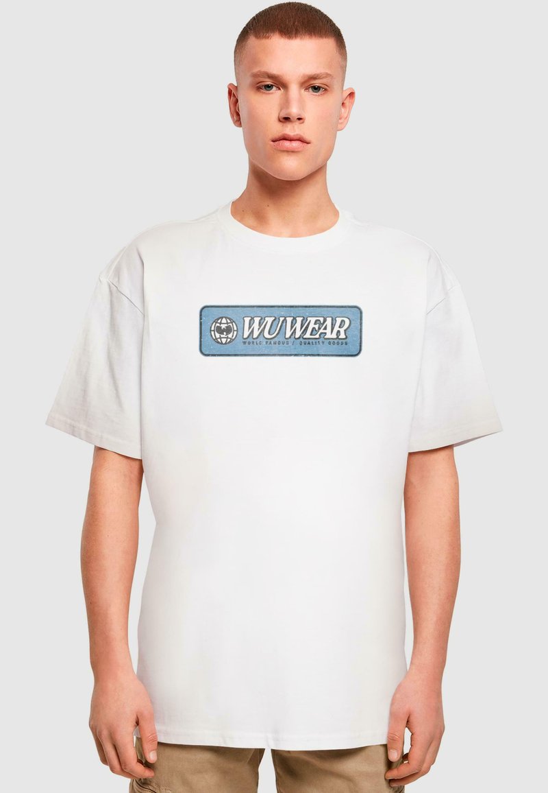 Hvid bomulds t-shirt med et blåt rektangulært logo med teksten 'WUWEAR'. Løs pasform, korte ærmer, minimalistisk design.