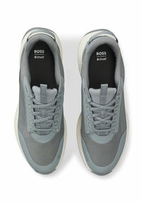 Szare sportowe trampki z teksturowanymi panelami z siateczki, dopasowanymi sznurowadłami i amortyzowanymi podeszwami. Na języku i wkładkach znajduje się logo.