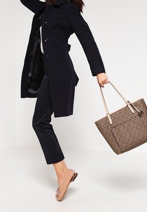 Manteau en laine marine, pantalon noir à motifs, ballerines marron clair et sac fourre-tout tan avec des bretelles, doté d'une poche avant.
