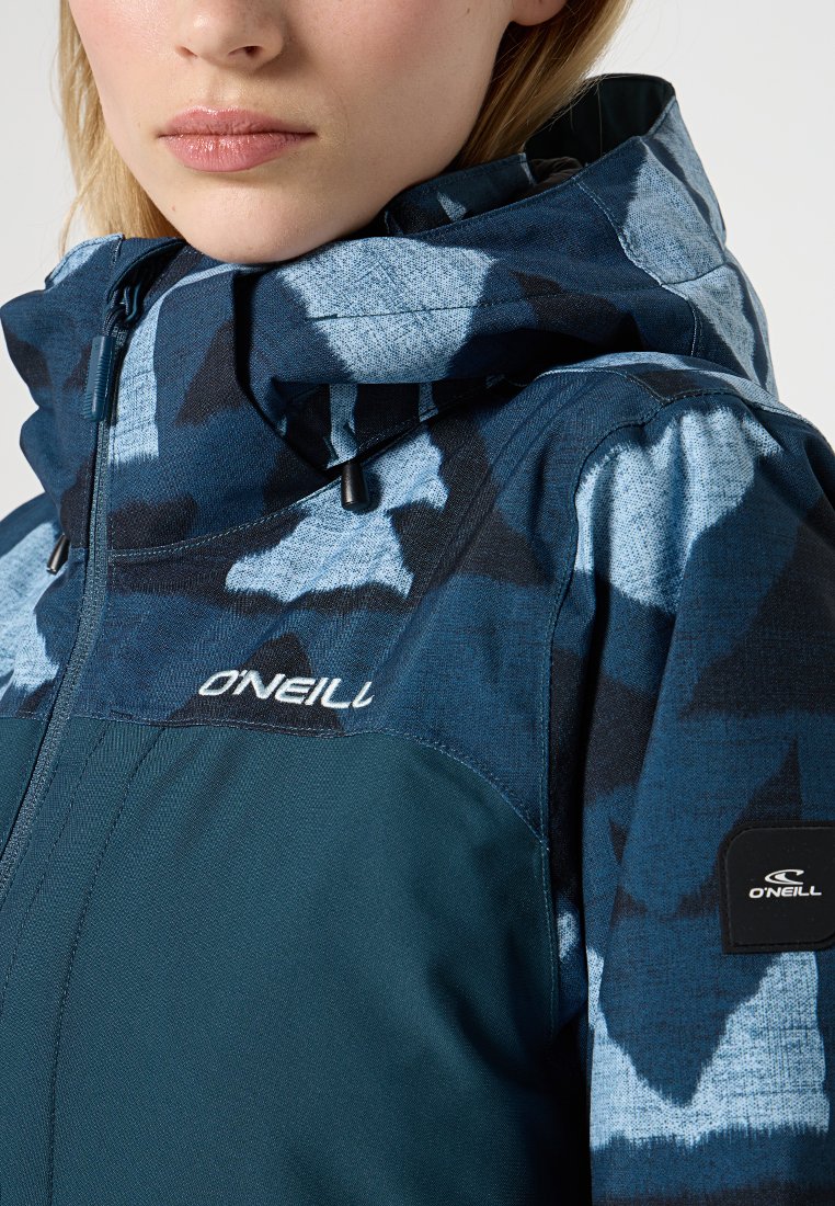 Blau gemusterte Jacke aus strukturiertem Stoff mit hohem Kragen, verstellbare Kapuze und Logo auf der Brust und dem Ärmel, das ein markantes Design hervorhebt.