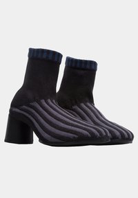 Knitted ankle boots in black and gray stripes, featuring a contrasting blue striped ribbed cuff and a black block heel.