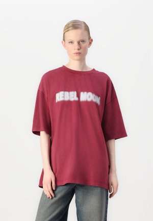 Bordeaux oversized t-shirt van katoen, met een witte "REBEL MOON" graphic over de borst en korte mouwen.