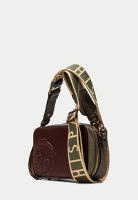 Borsa in pelle marrone e verde oliva con lettering in rilievo "Since 90", scomparti con zip e una tracolla regolabile decorata.