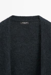 Ciemnoszary sweter z dzianiny o miękkiej, puszystej fakturze, z otwartym przodem i metką z napisem "Massimo Dutti, Wyprodukowano we Włoszech."