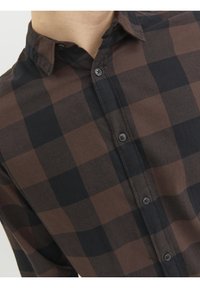 Camicia abbottonata in plaid marrone scuro e nero; materiale in cotone; presenta un colletto a punta e chiusura frontale con bottoni; texture liscia.