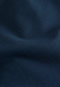 Țesătură albastru închis cu o textură moale, subtilă și pliuri delicate care creează umbre și reflexii fine.