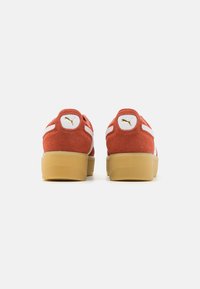 Suede orange sneakers with white accents, padded collar, and textured rubber sole. Gold logo detail at the heel.