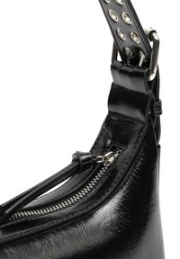 Sac à main en cuir noir de forme arrondie, doté d'une fermeture éclair et d'une sangle décorative cloutée. Surface texturée avec une finition brillante.