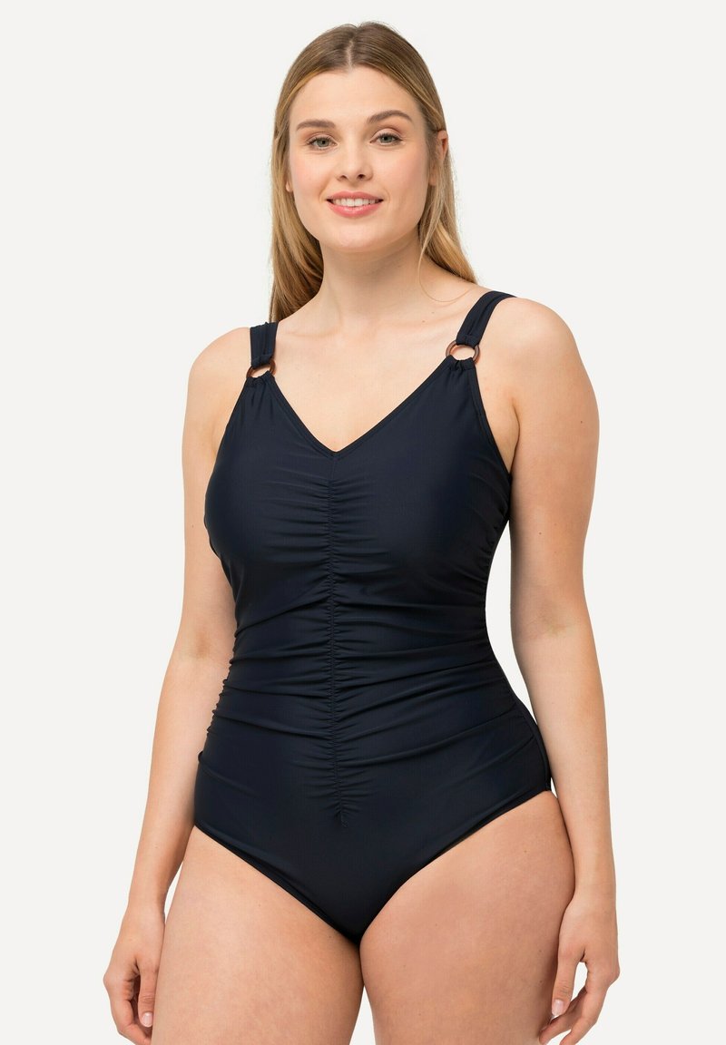 Maillot de bain une pièce noir avec un décolleté en V, un design froncé, des bretelles ajustables et des accents en métal rond. Texture de tissu lisse.