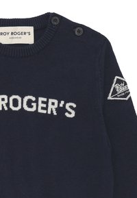 Maglione lavorato a maglia blu navy con il testo bianco "ROGER'S". Presenta un collo rotondo, due bottoni sulla spalla e una toppa a logo triangolare sulla manica.