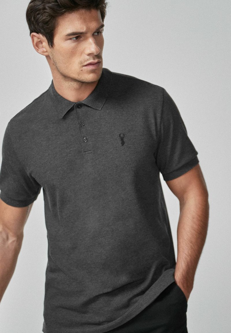 Mørkegrå polo shirt i bomuldsblanding, med klassisk krave, tre knapper og et diskret broderet logo på venstre bryst.