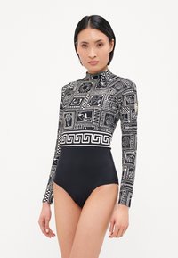 Body à manches longues noir avec un haut à motifs présentant des designs géométriques et un col montant. Matériau lisse avec une coupe ajustée.