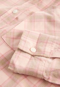 Lichtroze geruite blouse met een knoopsluiting aan de kraag, een textuurstof en contrasterende gestreepte manchetten met witte knopen.