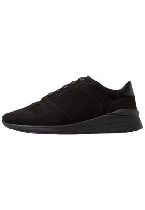 Czarny niski sneaker z siateczkowymi panelami bocznymi, czarne sznurówki i grubą gumową podeszwą, widok na zewnętrzną lewą stronę.