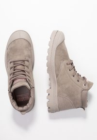 Botas de tobillo beige con parte superior de ante texturizado, suela de goma y cuello acolchado. Presenta cordones redondos y ojales de metal.