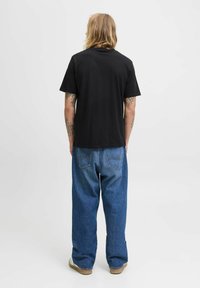 Sort bomulds t-shirt med korte ærmer, parret med blå denim jeans med afslappet pasform, baglommer og synlige syninger.