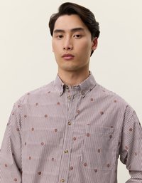 Camisa de botones en rayas burdeos y blancas con pequeños detalles en un patrón marrón. Presenta un collar, bolsillo en el pecho y un corte holgado.