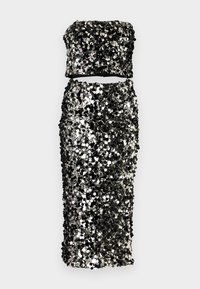 Vestido de dos piezas en negro y plata con lentejuelas, que presenta una parte superior sin tirantes y una falda ajustada de cintura alta. Textura suave con superficie reflectante.