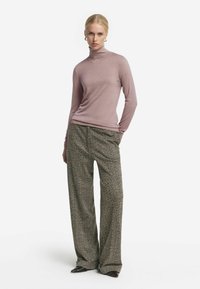 Ljust rosa polotröja med långa ärmar, i kombination med byxor med vida ben i hundtandsmönster. Stickad struktur med subtila detaljer.