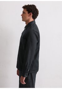 Donkergrijs, shirt met lange mouwen, een kraag en een borstzak. De stof lijkt een textuur te hebben, met een nauwsluitende pasvorm en manchetten met knopen.