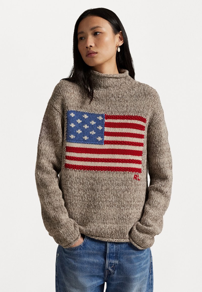 Pletený sveter v béžovej farbe s výrazným dizajnom americkej vlajky, ktorý obsahuje modrú, červenú a bielu farbu a má vysoký golier.