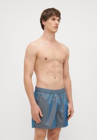 Herrebadebukser laget av lett, blank blått stoff med elastisk liv, som har en avslappet passform og ingen synlige mønstre.