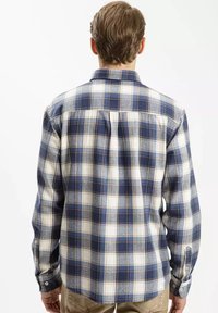 Koszula w kratę w niebieskich, białych i szarych odcieniach. Długie rękawy, mankiety na guziki, kołnierzyk i luźny krój. Bawełniana tkanina o miękkiej fakturze.