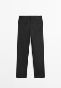 Schwarze, maßgeschneiderte Hose mit Gürtelschlaufen und zwei Gesäß-Paspeltaschen, flach liegend vor weißem Hintergrund dargestellt.