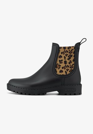 Botas de tobillo de goma negra con un panel de tela de leopardo, suela texturizada y marca en el talón. Cuenta con una cinta de agarre para facilitar su uso.