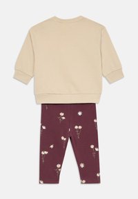 Zweiteiliges Kinderoutfit mit einem beigen Langarm-Sweatshirt und burgunderfarbigen Leggings mit weißen Blumenmustern. Hergestellt aus weichem Baumwollmaterial.