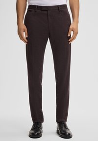 Dunkelgraue maßgeschneiderte Hose aus strukturiertem Stoff, mit flacher Vorderseite und zwei Seitentaschen. Kombiniert mit schwarzen Dressschuhen.
