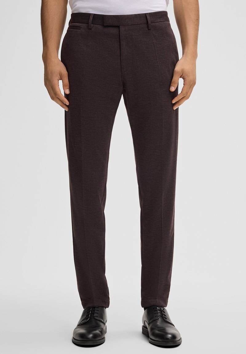 Dunkelgraue maßgeschneiderte Hose aus strukturiertem Stoff, mit flacher Vorderseite und zwei Seitentaschen. Kombiniert mit schwarzen Dressschuhen.