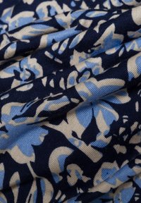 Tessuto navy con motivo floreale in azzurro chiaro e crema, realizzato in materiale morbido con una leggera trama e delle pieghe.
