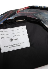 Interior negro de una bolsa con una etiqueta blanca que tiene campos rellenables para información personal, rodeada de una tela estampada colorida.