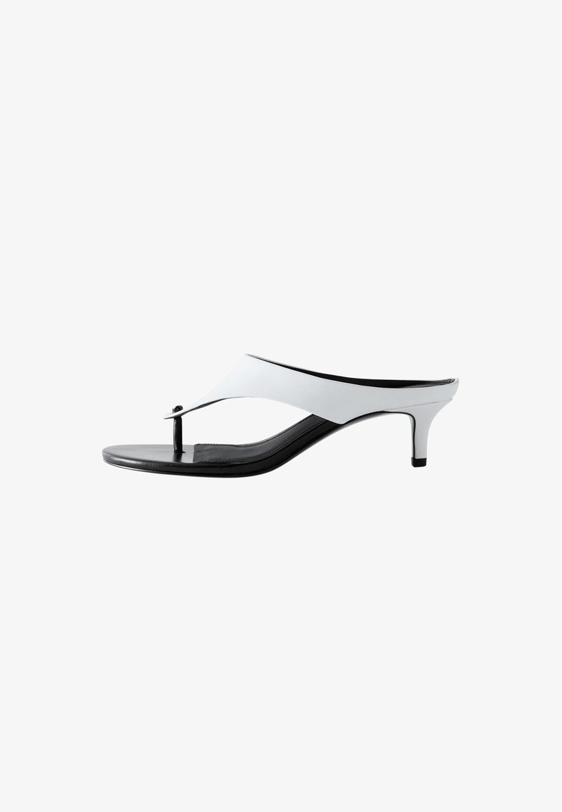 Sandale à talon bride entre les orteils blanche et noire pour femme, avec un talon fin de hauteur moyenne et un design minimaliste.