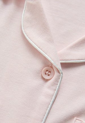 Light pink fabric with a subtle texture, featuring a white piped collar and a round, pink button. The design includes a classic pajama aesthetic.
