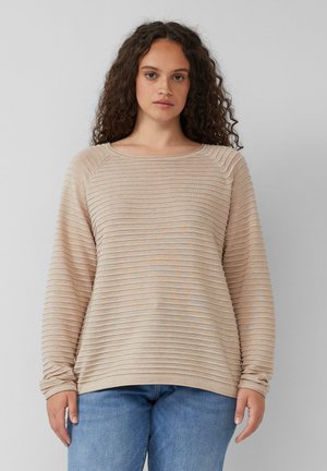 Beige long-sleeve top with horizontal ribbed texture, round neckline, loose fit, and rolled cuffs paired with blue jeans.