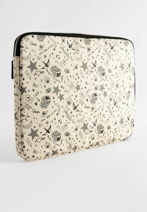 Husa de laptop crem cu model de tatuaje, având desene cu cerneală neagră de stele, ochi, inimi și diverse simboluri; închidere cu fermoar și textură fină.