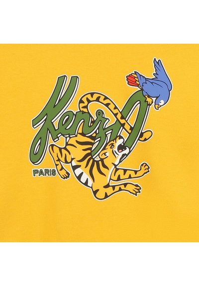 Tissu jaune avec un imprimé graphique d'un tigre et d'un oiseau bleu, avec le texte "Kenzo Paris" en vert. Texture lisse, couleurs vives.