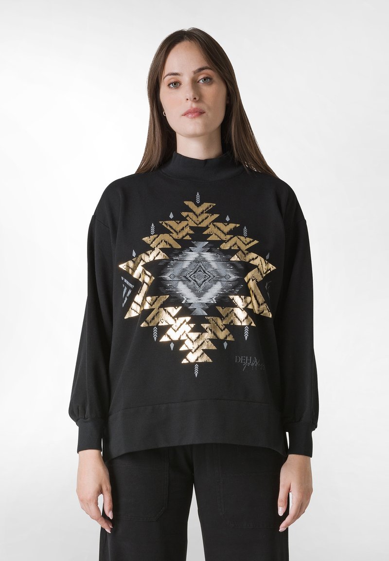 Svart sweatshirt med ett guld- och silverfärgat geometriskt mönster centrerat på bröstet, hög krage och löst sittande ärmar.
