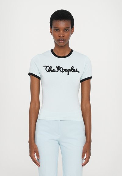 Tricou scurt, de culoare albastru deschis, cu manșete și guler ribbed negre, având textul cursiv negru "The Kvyples" pe piept.