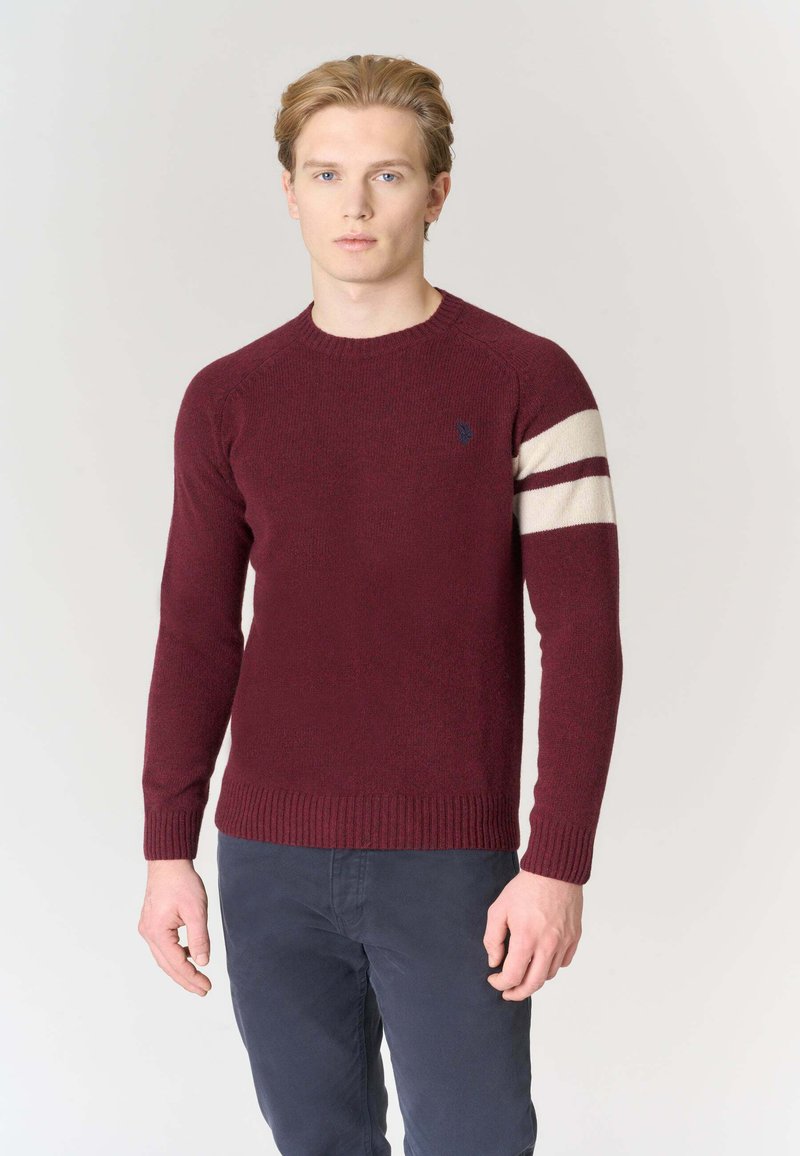 Maglione bordeaux lavorato a maglia con maniche lunghe, con orlo a coste e una striscia cremisi sul braccio sinistro. Piccolo logo sul petto.