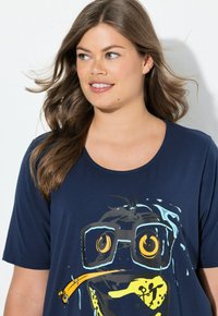 Námorně modré tričko s kulatým výstřihem, na kterém je grafika kreslené postavičky s brýlemi, žlutým zobákem a vodními stříkanci.